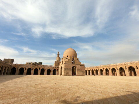 View of the historic Mosque of Ibn Tulun with its iconic dome and minaret set against a clear blue sky in Bab Al Louq, Cairo Governorate, Egypt.
