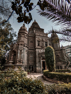View of the ornate facade of the historic Said Halim Pasha Palace, featuring intricate stone carvings and arched windows, framed by lush garden foliage in Bab Al Louq, Cairo Governorate, Egypt.