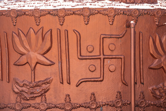 View of a copper-colored relief carving featuring a lotus flower and a swastika symbol on a temple wall in Pokhara, Gandaki Province, Nepal.