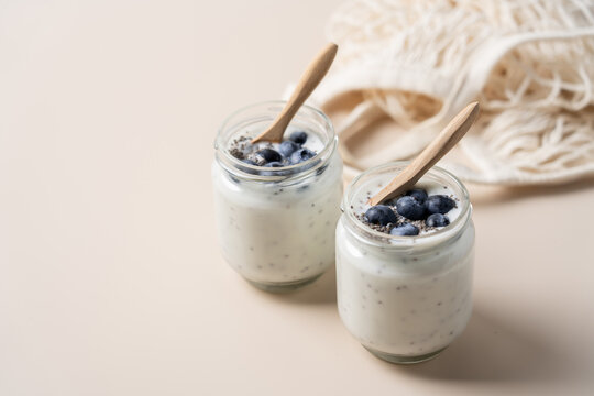 Healthy chia seed yogurt with fresh blueberries in glass jars on a light beige background, nutritious breakfast and clean eating concept for healthy lifestyle, wellness and balanced nutrition