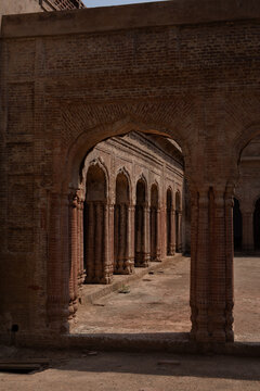 View of the historic Haveli of Maharaja Ranjit Singh featuring intricate brick arches and columns in a courtyard setting in Gujranwala, Punjab, Pakistan.