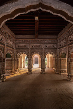 View of the historic Bara dari at Sheranwala Bagh featuring intricate frescoes and arched stone pillars illuminated by warm sunlight in Gujranwala, Punjab, Pakistan.