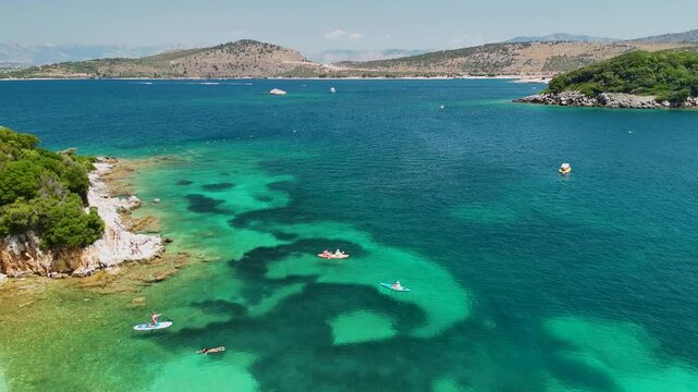 Woman on sup board in Ksamil near Twin Islands, Ionian Sea, Saranda, Albania. Stand up paddle board woman paddle boarding. Aerial panoramic drone view from above, top view from drone. Mediterranean se