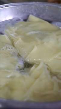 Close-up of fresh dough sheets boiling in hot water inside a metal pot for traditional beshbarmak