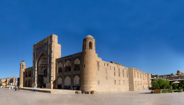 View of the historic Abdulaziz Khan Madrassah with its intricate blue tilework and arched entrance under a clear blue sky in Buxoro, Buxoro Viloyati, Uzbekistan.