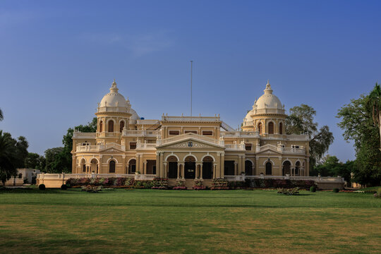 View of the historic Gulzar Mahal palace with its elegant domes and lush green lawn under a clear blue sky in Bahawalpur, Punjab, Pakistan.