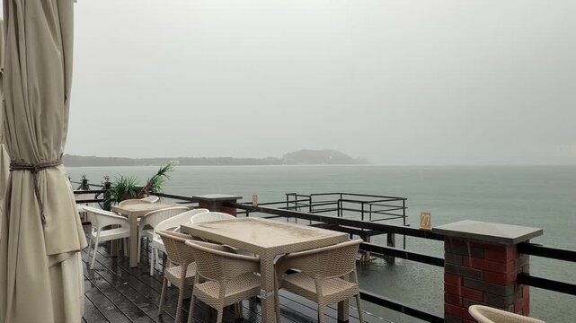 Rainy day at a lakeside summer cafe, empty outdoor terrace and peaceful off-season atmosphere under an overcast sky