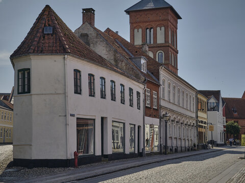 View of historic white and red brick buildings with tiled roofs along a cobblestone street in Ribe, Denmark.