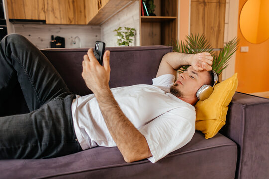 Man relax on sofa with smartphone and headphones