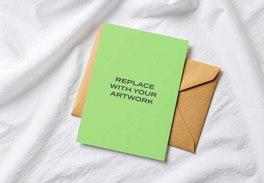 Greeting card mockup with brown envelope on white textured fabric surface, flat lay stationery presentation template for branding, design, print, and commercial use