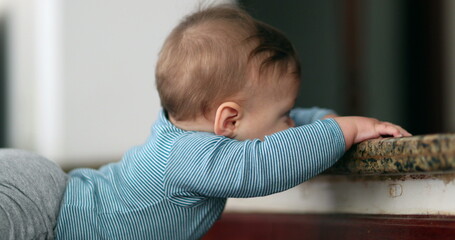 Fototapeta premium Baby learning to climb doorstep stair. Infant toddler development and effort