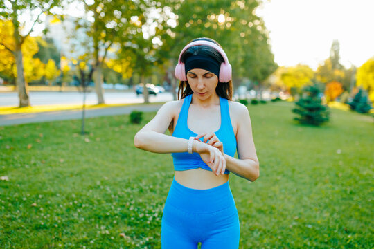 Active fit woman checking her smartwatch in the sunny summer park.
