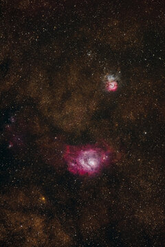 View of the Lagoon Nebula and the Trifid Nebula glowing in the deep space of the night sky, captured with long exposure astrophotography in Sopotnia Wielka, Silesian Voivodeship, Poland.