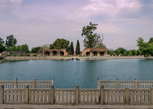 View of Mughal Gardens Wah with its historic stone structures, reflecting pool, and lush trees under a cloudy sky in Wah, Punjab, Pakistan.