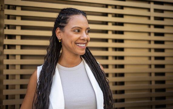 Smiling Latin woman with braids against a patterned wall