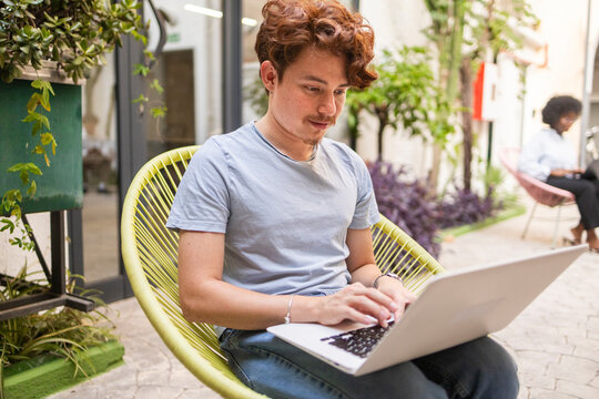Young professional work on laptop in coworking office courtyard
