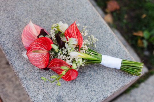 Bridal bouquet with red anthurium on stone bench