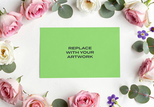 Rectangular card mockup with placeholder text surrounded by pink and white roses eucalyptus leaves on a surface, flat lay stationery branding presentation template