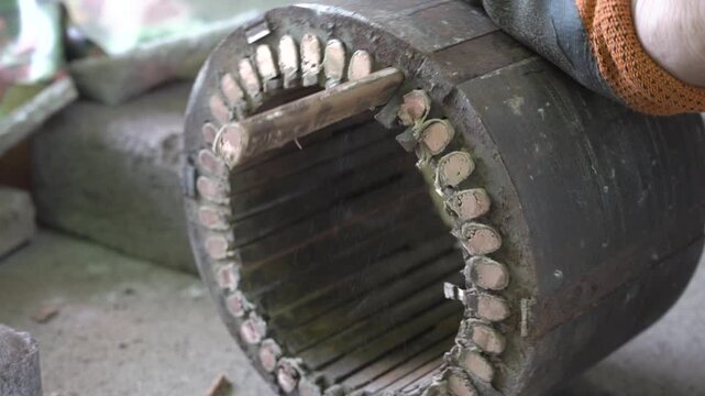 Man clearing copper windings from old electric motor stator close up, Process of cleaning copper windings of a motor for scrapping