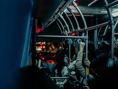 Crowded public bus interior with hanging handles and night city lights
