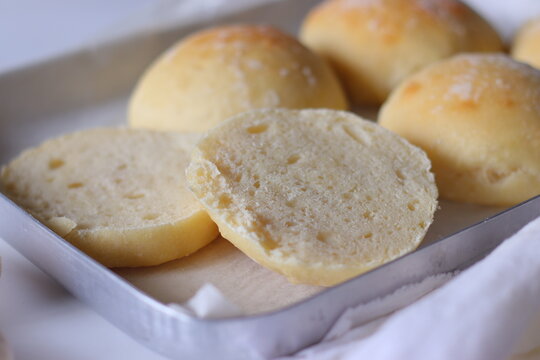 Homemade ciabatta bread rolls arranged on a parchment lined baking tray with sliced pieces revealing the soft, airy crumb. Rustic food styling highlights texture, freshness, and artisan baking