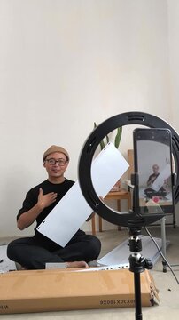 Asian man content creator filming DIY Furniture assembly tutorial with ring light, vlogging, live stream selling, social media influencers, online home improvement guides, and product review videos.