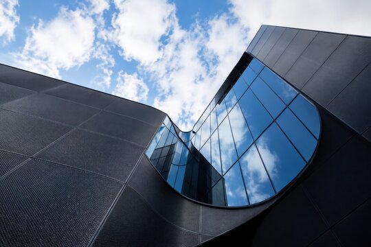 Modern office building facade with glass windows reflecting blue sky