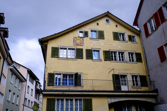Zurich, Switzerland - March 15, 2026. Historic Zum Sunnezyt Building with Decorative Sundial in Zurich. A low-angle exterior view of the historic "Zum Sunnezyt" building located in the Old Town