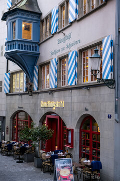 Zurich, Switzerland - March 15, 2026. Historic Zum K&ouml;nigstuhl Restaurant with Blue Striped Shutters in Zurich. A vertical, high-angle view showcases the historic Zum K&ouml;nigstuhl restaurant and guild ho