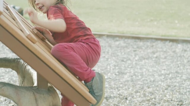Two boys climbing a wooden playground frame in warm backlit sunshine