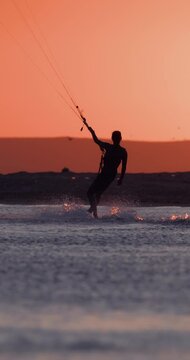 Kite surfer riding on water during a sunset