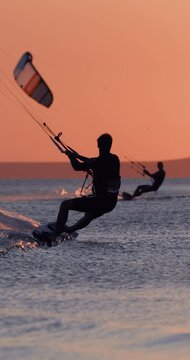 Kite surfer riding on sea water with warm sunset light