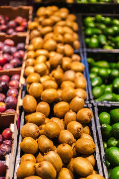 Fresh kiwi fruits and avocados displayed in supermarket produce section with colorful tropical fruits and healthy grocery shopping concept