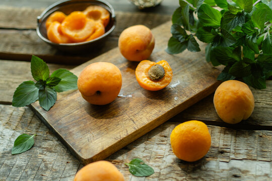 Fresh apricots with mint leaves on wooden table. Summer seasonal fruits.
