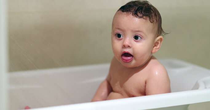 Bathing cute baby. Washing adorable toddler inside bathtub