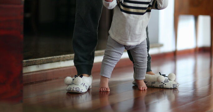 Baby learning to walk. Mother helping toddler infant to stand-up indoor