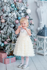 Fototapeta premium Child holds ornament by Christmas tree in winter