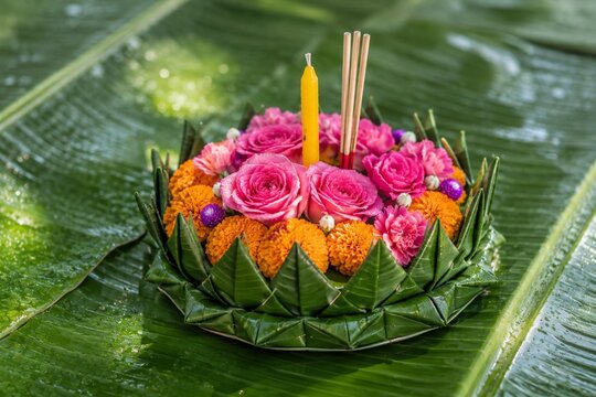 Floral krathong with candle and incense on banana leaves