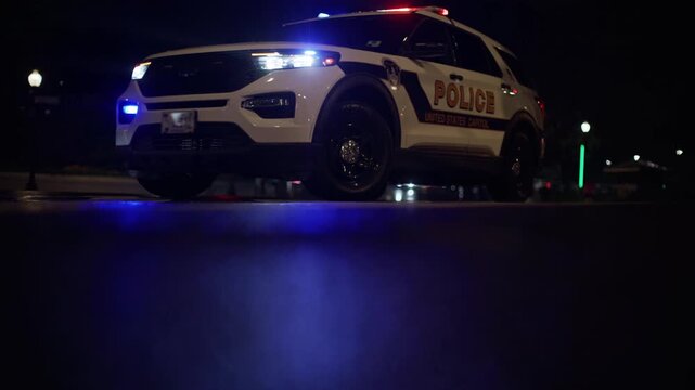 Police car with red and blue lights. Federal police vehicle with emergency lights. Police SUV from low angle view. United States Capitol police vehicle at night.