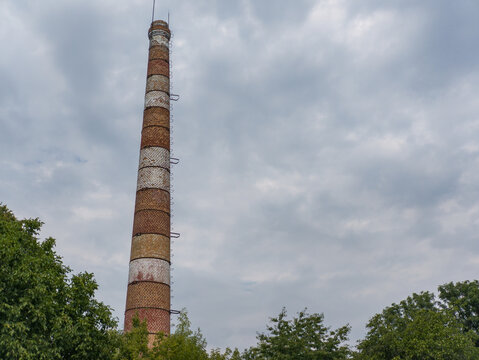 Industrial brick smokestack tower rising above green forest tree tops