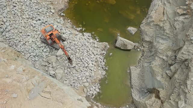 Excavator Breaking Stone in Deep Quarry From Above