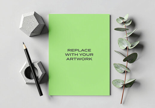 Vertical paper mockup with placeholder text displayed on a flat surface, surrounded by concrete geometric objects, pencil, and eucalyptus branch, Template