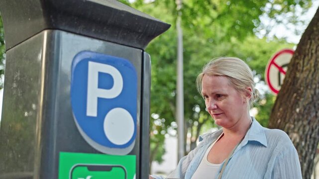 Woman paying for parking at street meter