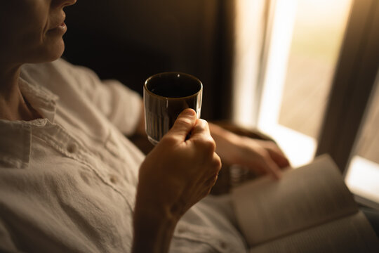 Person relaxing at home reading book feeling relaxed on a cozy morning enjoying cup of hot tea coffee	