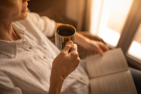 Person relaxing at home reading book feeling relaxed on a cozy winter morning enjoying cup of hot tea coffee	