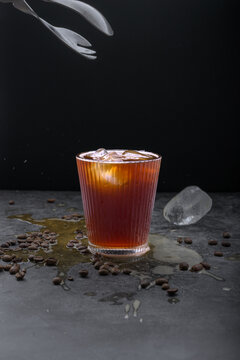 Refreshing iced coffee cocktail with orange slice ice cubes vintage manual grinder and scattered roasted coffee beans on dark surface
Keywords