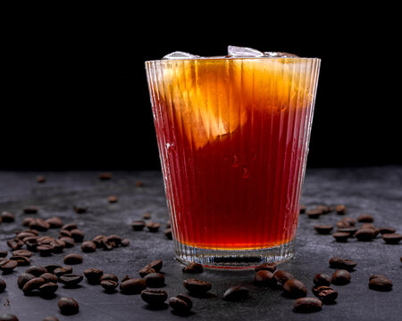 Refreshing iced coffee cocktail with orange slice ice cubes vintage manual grinder and scattered roasted coffee beans on dark surface
Keywords