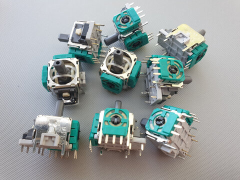 Nine individual controller joystick modules scattered on a grey background