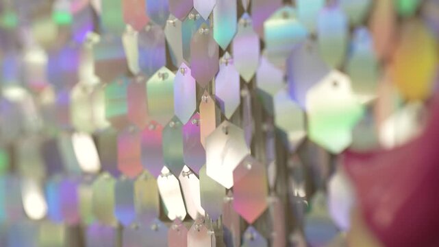Shiny holographic hexagonal sequins create a vibrant iridescent background pattern with reflective metallic surfaces and dynamic color shifts for contemporary design projects