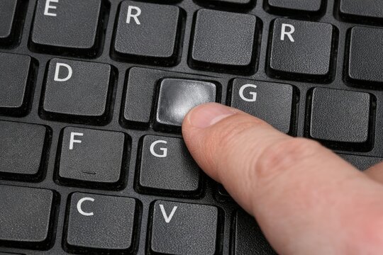 A close-up of a finger pressing a button on a computer keyboard